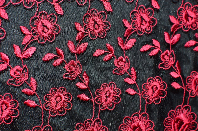 Motifs floraux brodes sur tissu noir : roses, feuilles et fleurs traditionnelles